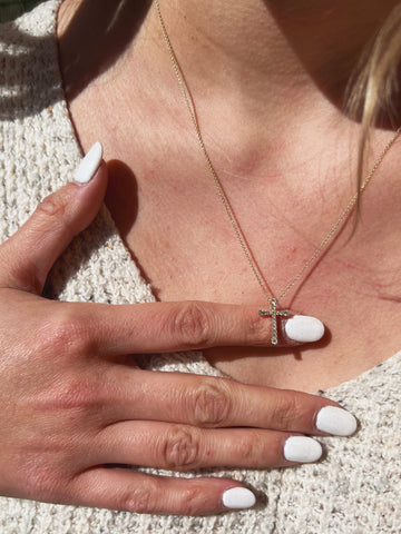 Woman Wearing Dainty Cross Necklace with Cream Sweater