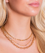 Model wears three gold chain necklaces from Fink's Jewelers