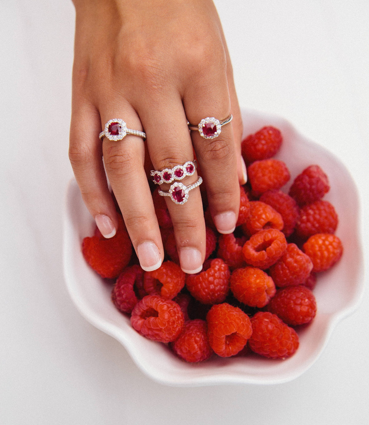 Woman wearing ruby rings and a bowl of raspberries