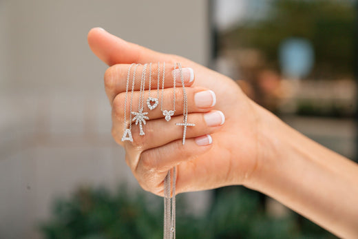 hand holding different necklaces with small pendant on each