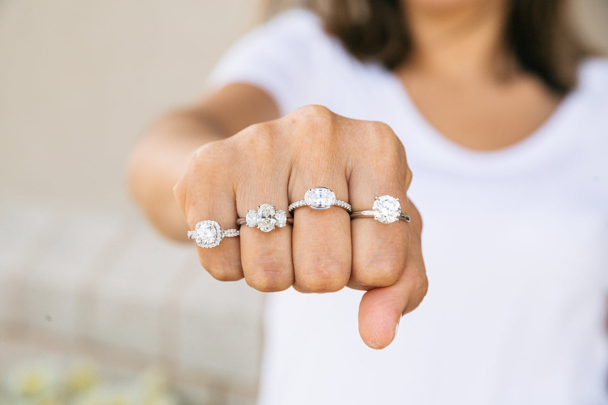 Woman modeling four different engagement ring styles and diamond cuts