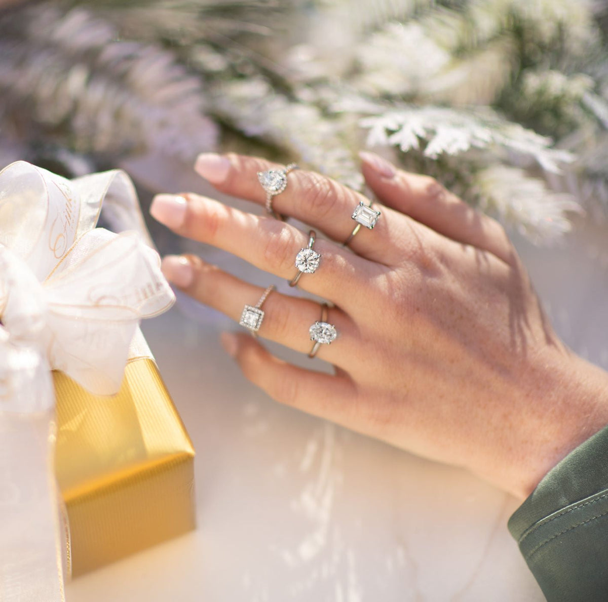 Woman's hand displaying five diamond engagement rings from Fink's Jewelers