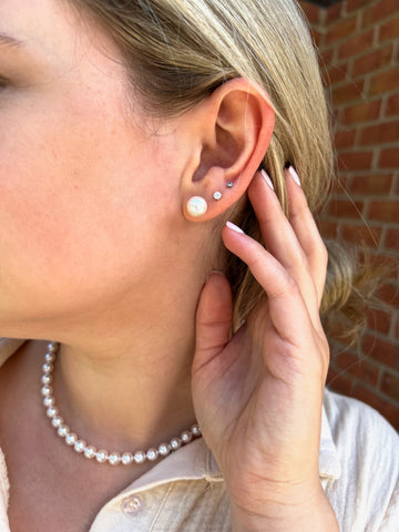 Woman wearing pearl stud earrings and with matching necklace
