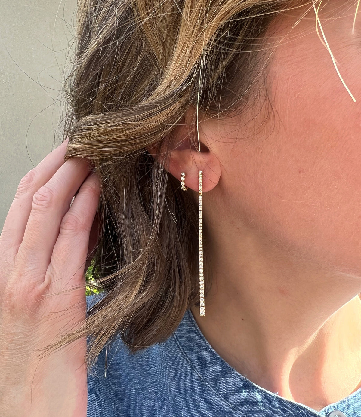 Woman models long drop earrings with diamonds