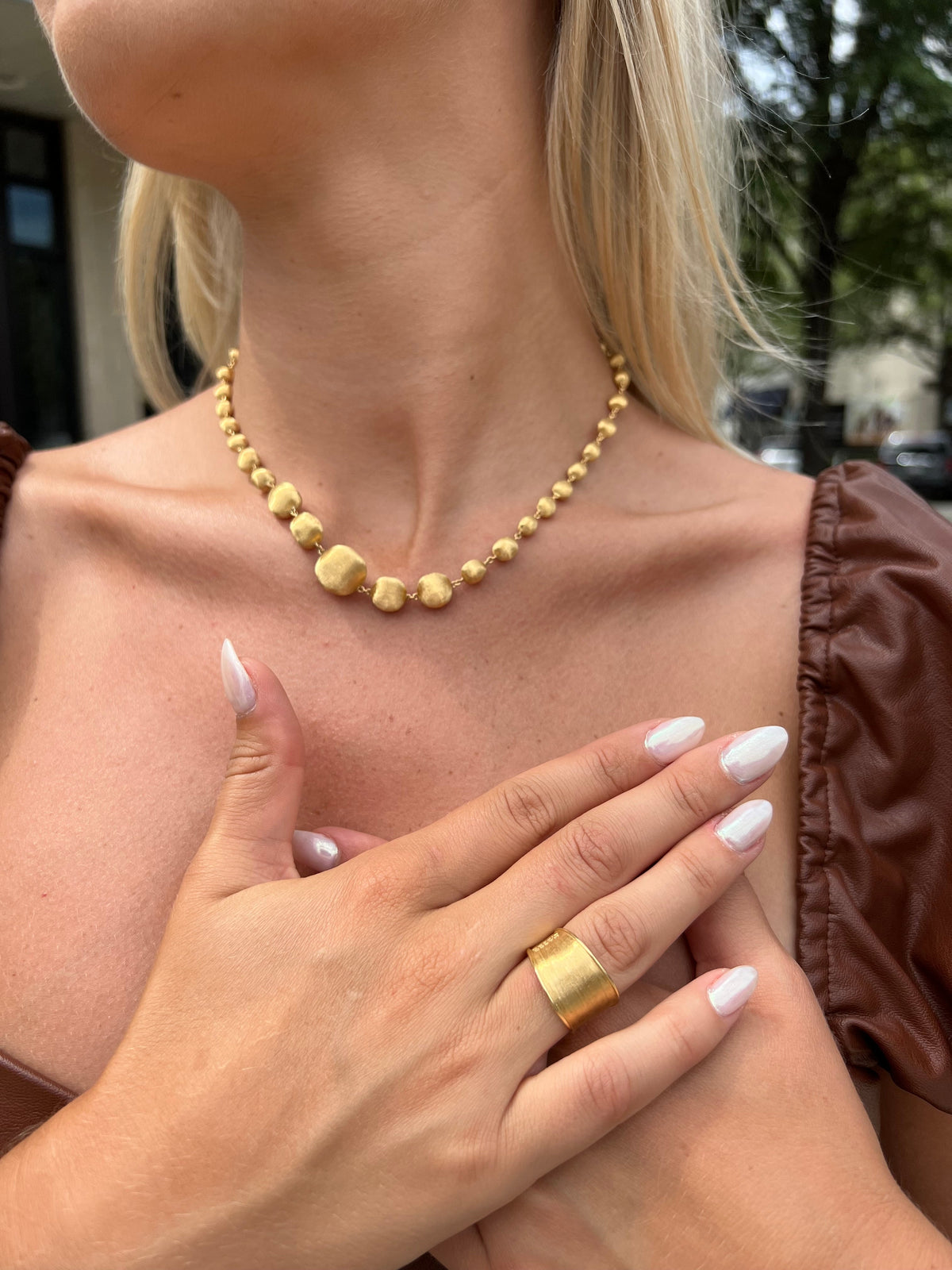 Woman wearing yellow gold bead necklace and gold stacking ring from Fink's Jewelers