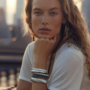 woman posing at camera with head resting on hand wearing David Yurman bracelets on arm