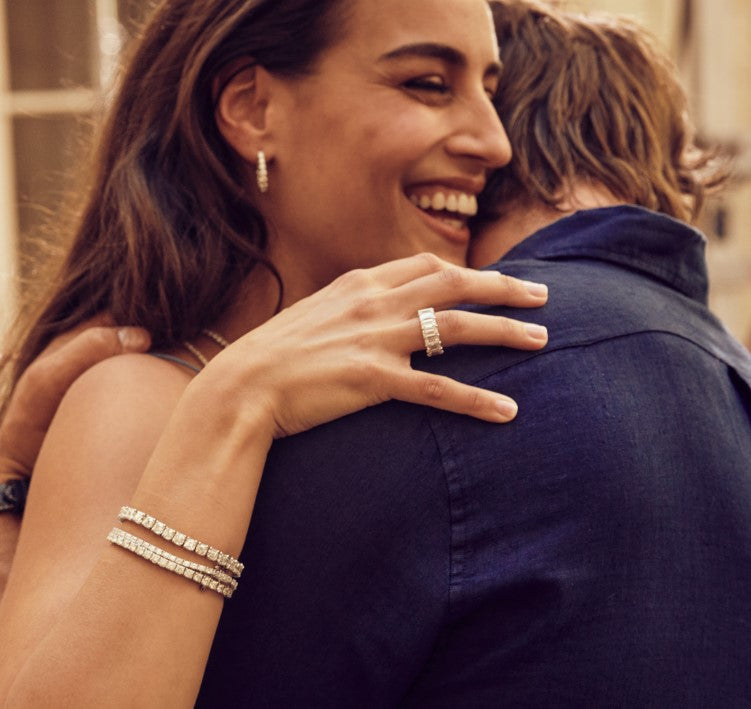Woman wearing anniversary jewelry while hugging her husband