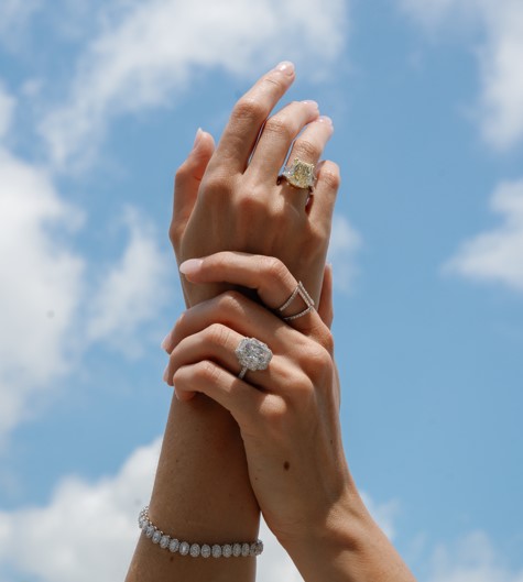Woman wearing diamond rings and bracelet with sky background