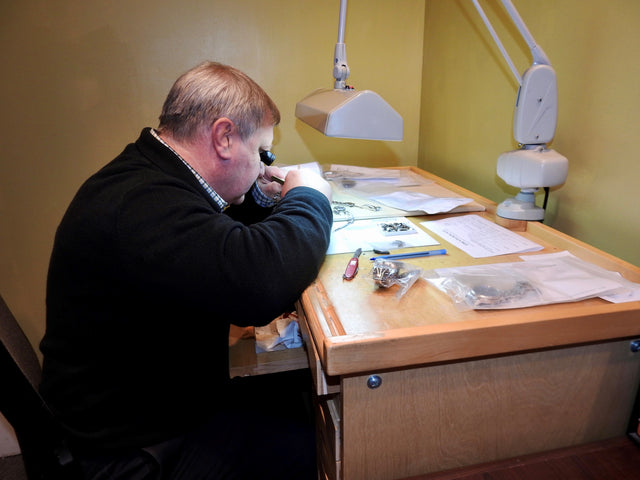 Watchmaker Inspects Luxury Timepiece for Repair at Desk