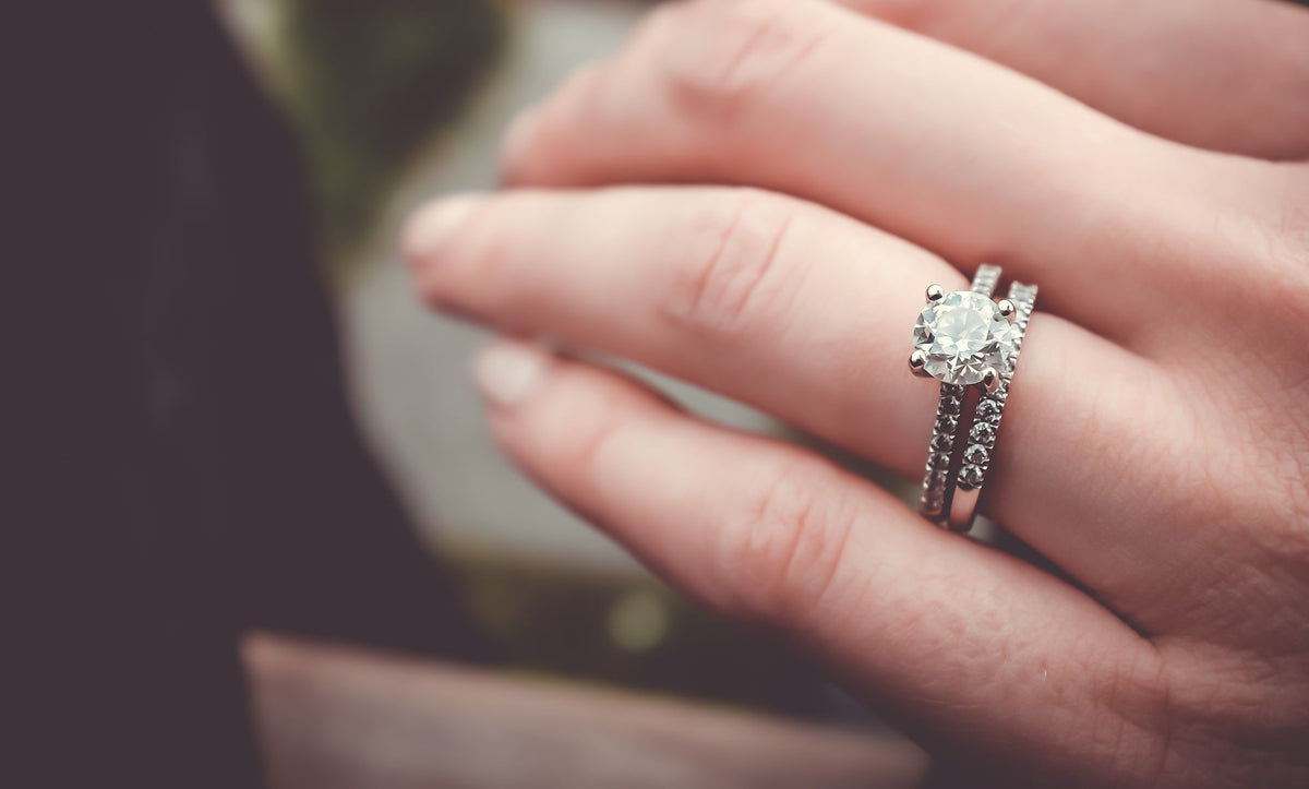 Fink's diamond engagement ring and wedding band on woman's finger