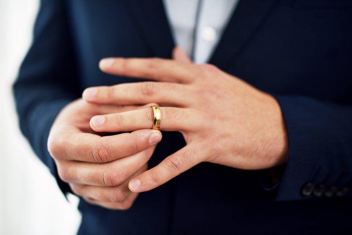 Man putting on his gold wedding band