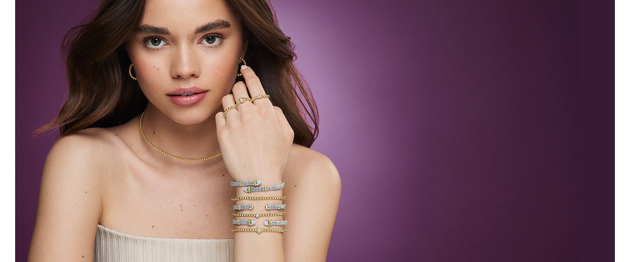 Woman wearing gold jewelry against a purple background