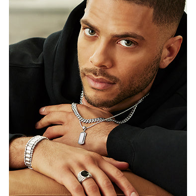 Man wearing silver jewelry including a necklace, bracelet, and ring.
