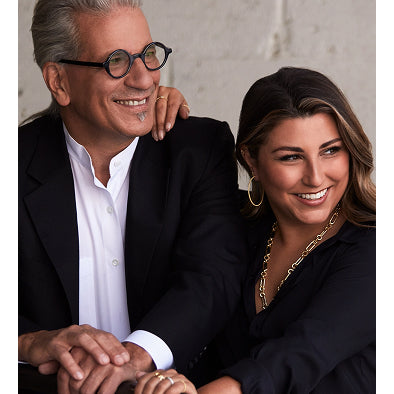 Man and woman sitting together, smiling, with a neutral background
