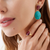Woman wearing Marco Bicego Lunaria Yellow Gold Thulite Ring with Gemstone Drop Earrings