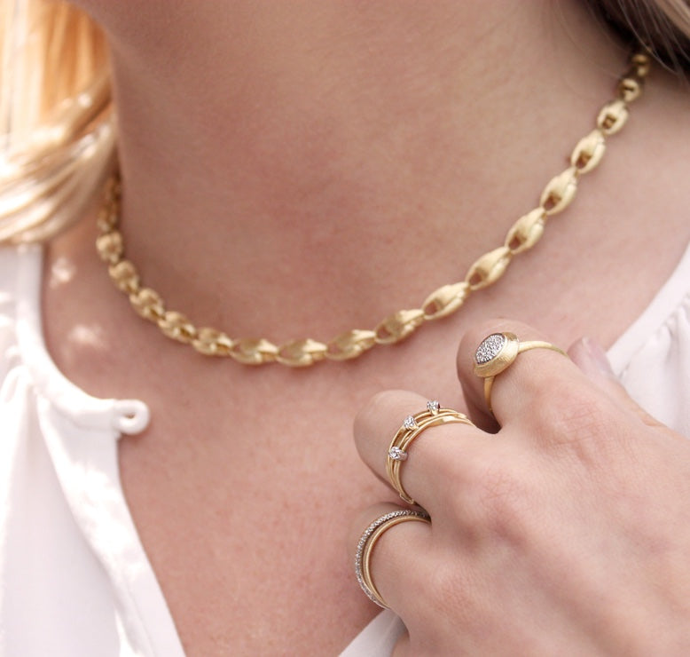 Woman wearing two gold rings and a gold necklace